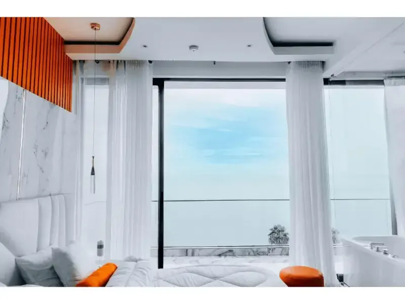 Bright bedroom at B&P Ever Retreat Villa with floor-to-ceiling windows facing Lake Kivu